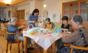 入居者と職員が食卓を囲んでレクリエーション活動を行っている風景