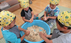 子どもたちが一緒に食材を混ぜる調理体験活動の風景